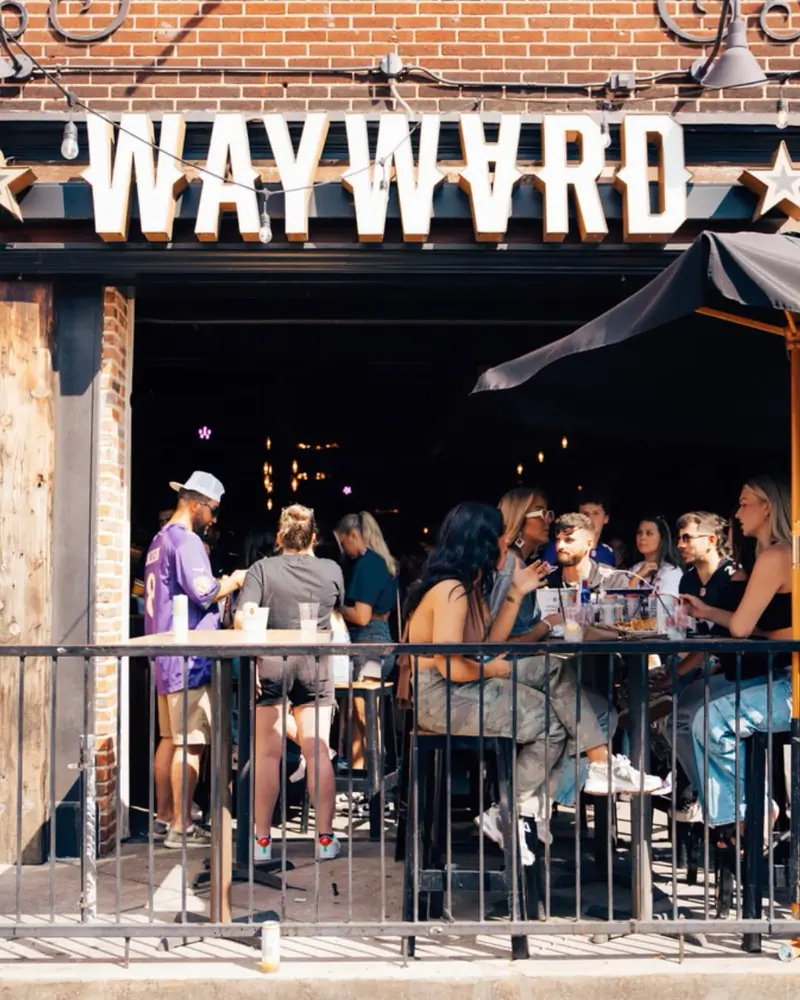A packed front patio under the Wayward sign