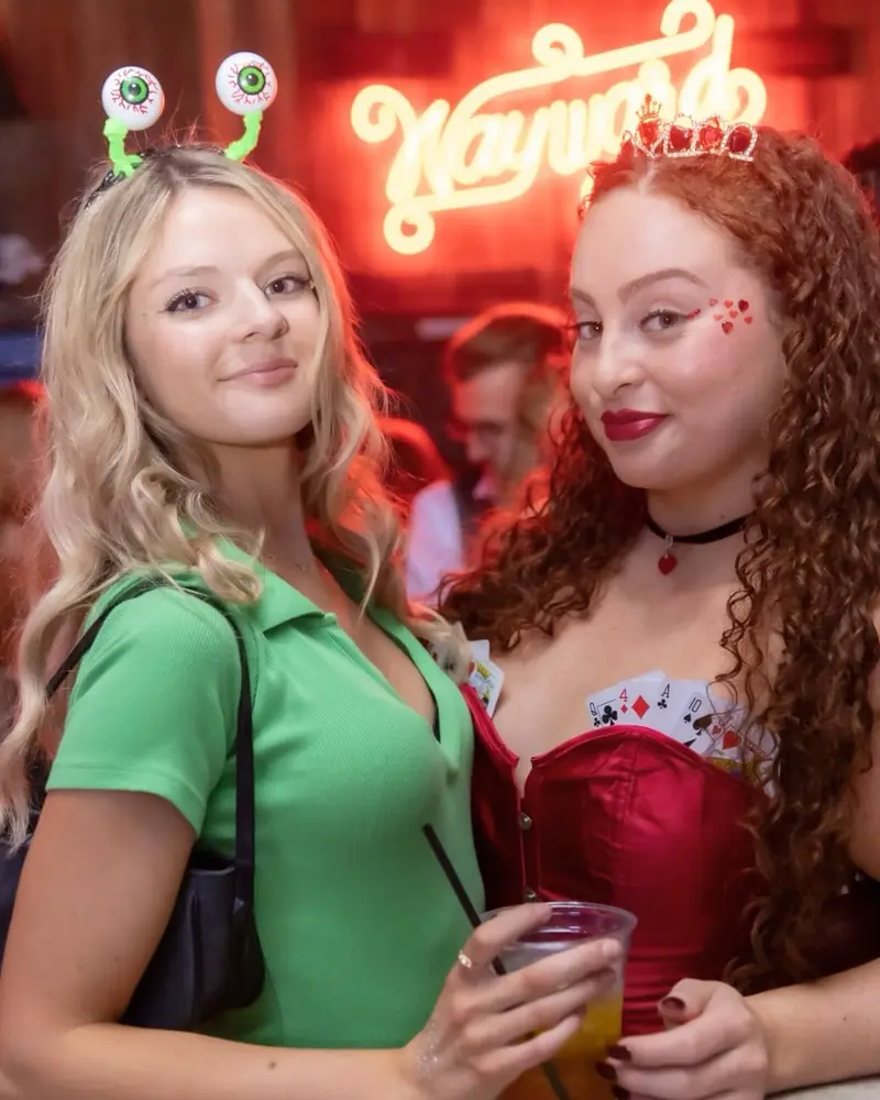 Two friends under the Wayward neon sign